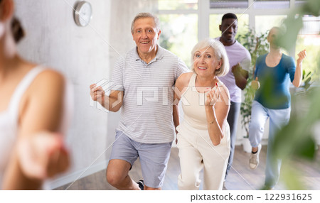 Senior man dances steamy salsa with elderly female companion for fitness classes Senior man dances steamy salsa with elderly female companion for fitness classes 122931625