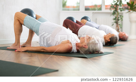 Lady does lightweight bridge pose - Setu Bandhasana and holds softball in lap. 122931626