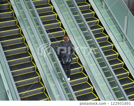 冬日早晨,一名年輕女子在購物中心搭乘自動扶梯 冬日早晨,一名年輕女子在購物中心搭乘自動扶梯 122931891
