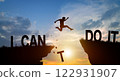 Silhouette man jumping over I can do it wording on cliffs with cloud sky and sunrise. Never give up, Good mindset, and Successful achievement Concept. 122931907