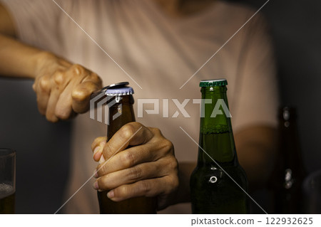 Hand of women opens lid fresh light beer. Beer is opened with help of bottle opener. 122932625