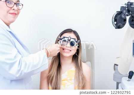 Female optometrist examining patient with optometrist trial frame. Smiling patient with optometrist trial frame 122932791