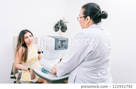 Optometrist with female patient in the autorefractor. Woman patient having consultation with optometrist in office 122932792