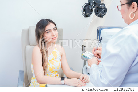 Female patient having consultation with optometrist in office. Optometrist with female patient taking notes in office. 122932795