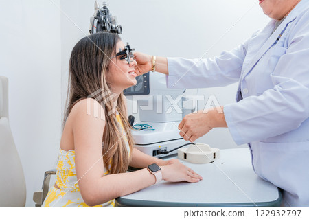 Optometrist woman examining patient with trial frame in office. Optometrist with young patient with optometrist trial frame 122932797