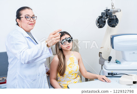 Optometrist assisting patient with optometrist trial frame. Patient with optometrist in a vision test with trial frame 122932798