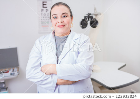 Portrait of female optometrist with arms crossed in the laboratory. Smiling female oculist with arms crossed in office Portrait of female optometrist with arms crossed in the laboratory. Smiling female oculist with arms crossed in office 122932824