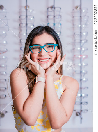 Portrait of a happy female customer wearing glasses in an eyewear store. Smiling girl wearing glasses in an eyeglass store 122932835