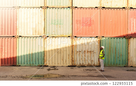 Logistics container, delivery and black man doing inspection of cargo at an outdoor distribution warehouse. African port manager planning shipping of stock while working in the supply chain industry 122933115