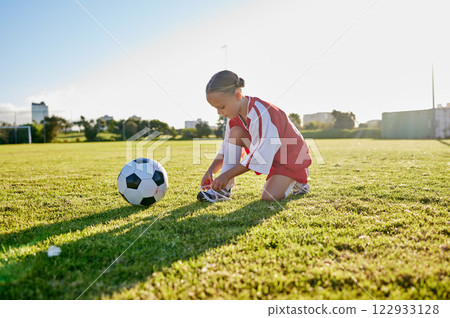Soccer, training and tie shoes with girl in sports workout for motivation, health and wellness. Exercise, growth and goals development with young child in football field for games, vision and fitness 122933128