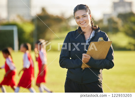 Soccer field, woman coach with and girl team training on grass in background. Sports, youth development and teamwork, a happy young female volunteer coaching football team with clipboard from Brazil. Soccer field, woman coach with and girl team training on grass in background. Sports, youth development and teamwork, a happy young female volunteer coaching football team with clipboard from Brazil. 122933203