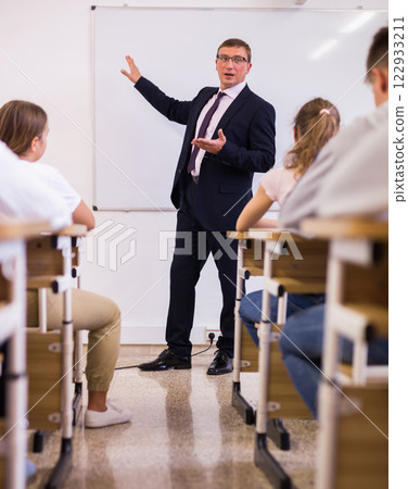 Male teacher lecturing to students at classroom Male teacher lecturing to students at classroom 122933211