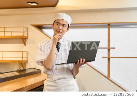 一位日本廚師拿著筆記型電腦，憂心忡忡 122933566