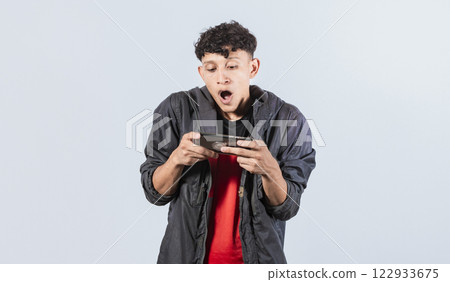 Man amazed holding cell phone horizontally, Guy gasping and playing games on his smartphone 122933675