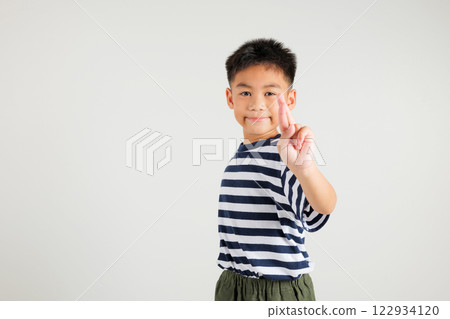 Asian happy portrait cute kid boy smile have superstition her holding fingers crossed for good luck or lie gesture studio shot isolated on white background, young primary child fraud hope for better 122934120