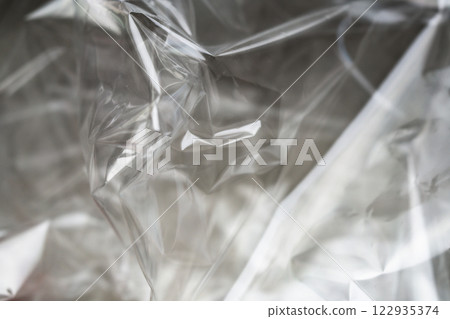 Crumpled clear plastic background, abstract glossy broken surface texture with creases 122935374