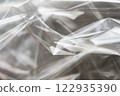 Crumpled clear plastic background, abstract glossy broken surface texture with creases 122935390