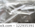 Crumpled clear plastic background, abstract glossy broken surface texture with creases 122935391