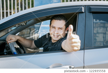 Happy Driver giving a thumbs up. Satisfied driver man showing thumb up. Concept of satisfied car owner, Man in his car giving thumbs up 122935558