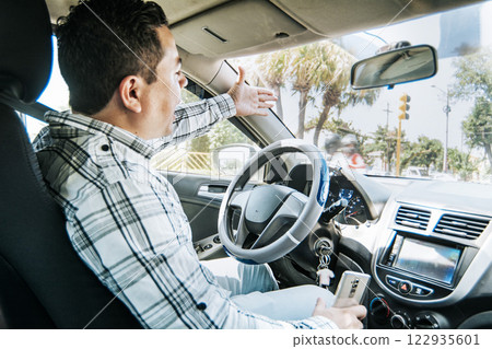 Stressed driver man yelling at other driver, Impatient driver yelling, portrait of angry driver yelling in his car, concept of impatient driver yelling Stressed driver man yelling at other driver, Impatient driver yelling, portrait of angry driver yelling in his car, concept of impatient driver yelling 122935601
