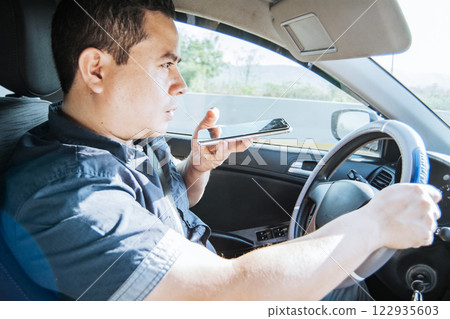 Man in his car sending voice notes with his cell phone, Side view of a young man sitting inside the car talking on the phone while driving, Young man sitting in the car talking on the phone while Man in his car sending voice notes with his cell phone, Side view of a young man sitting inside the car talking on the phone while driving, Young man sitting in the car talking on the phone while 122935603