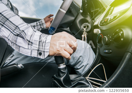 Close up of a man's hand on the gear lever of a car, concept of speed and gear lever, close up of hands accelerating on the gear lever 122935650