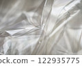 Crumpled clear plastic background, abstract glossy broken surface texture with creases 122935775