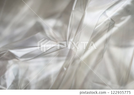 Crumpled clear plastic background, abstract glossy broken surface texture with creases 122935775