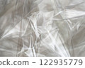 Crumpled clear plastic background, abstract glossy broken surface texture with creases 122935779