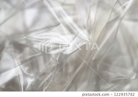 Crumpled clear plastic background, abstract glossy broken surface texture with creases 122935782