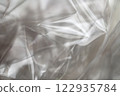 Crumpled clear plastic background, abstract glossy broken surface texture with creases 122935784