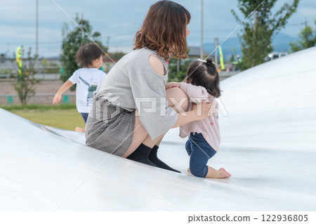 [母親和嬰兒站在巨大的遊樂場設備上] 122936805