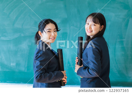 Female student holding a diploma in front of a blackboard 122937165