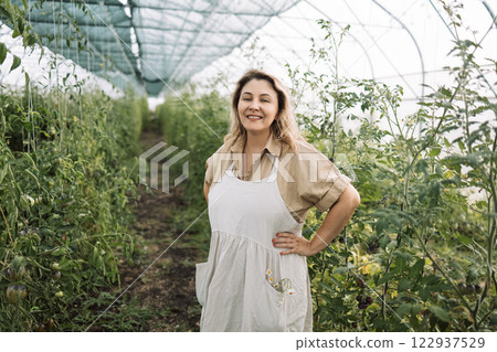 Closeup of a young attractive female farmer checking the ripe fruits of black tomatoes Closeup of a young attractive female farmer checking the ripe fruits of black tomatoes 122937529
