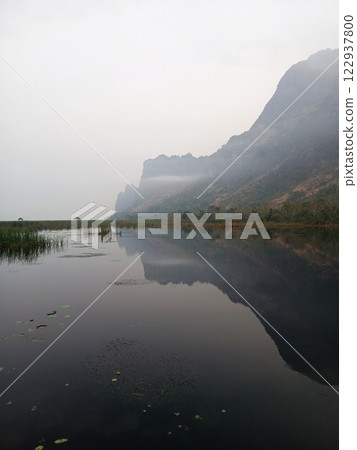 Wooden bridge and pavilion in wetland with the limestone mountain in mist , Path on the lagoon with reflection in water  , Khao Sam Roi Yot National Park , Thailand 122937800