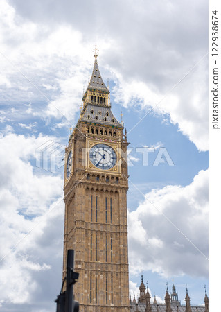Big Ben iconic clock tower bathed in daylight, emphasizing the golden accents and intricate design against the backdrop of a cloudy sky, for promoting London historic landmarks. 122938674