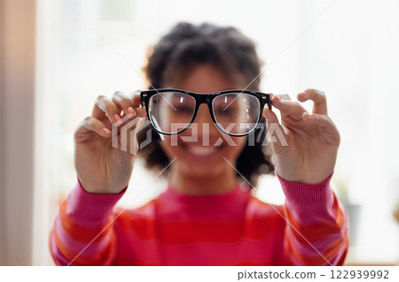 A young African woman smiles and keeps her glasses at home. A young African woman smiles and keeps her glasses at home. 122939992