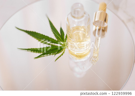 Mock up bottle cosmetic product and pipette with cannabis leaves on white glossy background 122939996