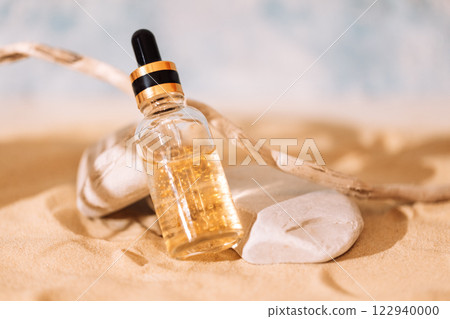 Mockup of bottle of cosmetics with pipette and transparent liquid with gold particles on sand. Sunscreen essence in glass tube on beach. 122940000