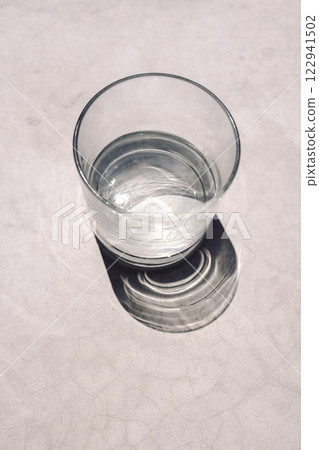 Close-up of a glass of clean water on a concrete table. Healthy mineral water and bright sunlight Close-up of a glass of clean water on a concrete table. Healthy mineral water and bright sunlight 122941502