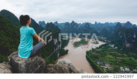 Woman meditating at the beautiful landscape of yangshuo county, China Woman meditating at the beautiful landscape of yangshuo county, China 122941997