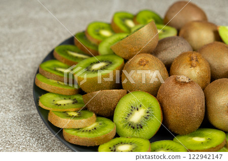 Plate of sliced and whole fresh kiwi fruit. 122942147