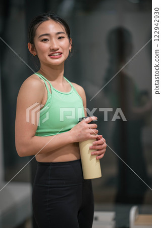 一名年輕女子在室內健身房鍛鍊間隙補充水分 122942930