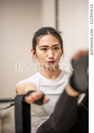 Young woman doing machine pilates in indoor gym 122943018