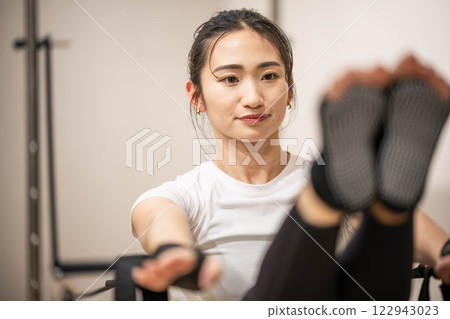 在室內健身房做機器普拉提的年輕女子 在室內健身房做機器普拉提的年輕女子 122943023