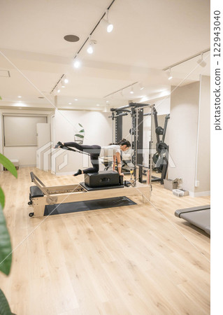 Young woman doing machine pilates in indoor gym 122943040