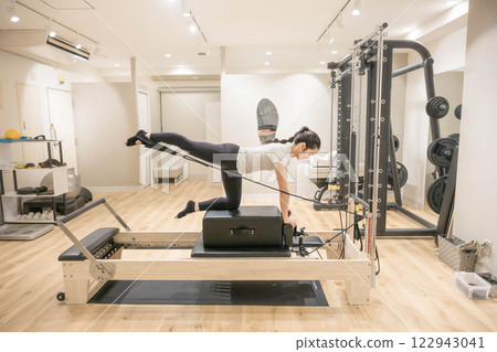 Young woman doing machine pilates in indoor gym 122943041