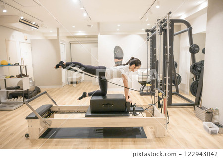 Young woman doing machine pilates in indoor gym 122943042