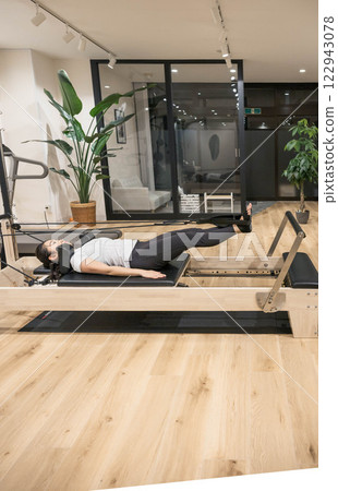 在室內健身房做機器普拉提的年輕女子 在室內健身房做機器普拉提的年輕女子 122943078