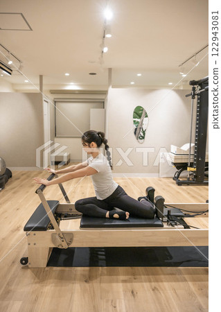 Young woman doing machine pilates in indoor gym Young woman doing machine pilates in indoor gym 122943081